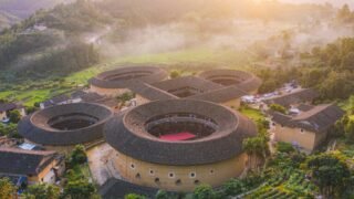 AI-generated illustration of circular Hakka tulou earth buildings in a green valley in Fujian, China