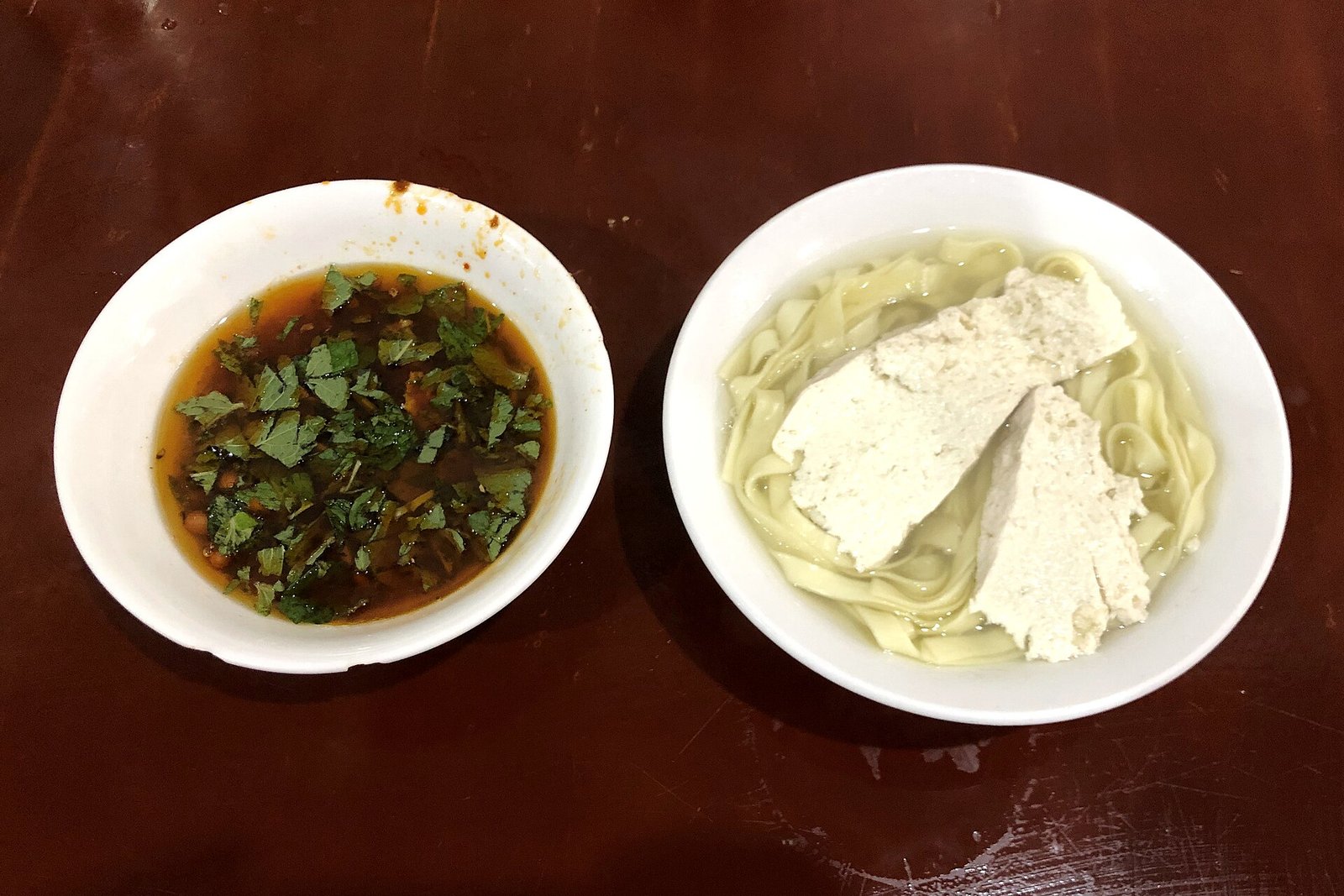 Bowl of Guizhou douhua noodles with soft tofu beside a separate bowl of chilli dip
