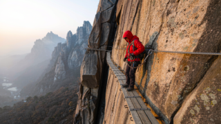 Huashan plank road hiker clipped to a steel cable on the Chang Kong Zhandao cliff walkway at 2,160 m