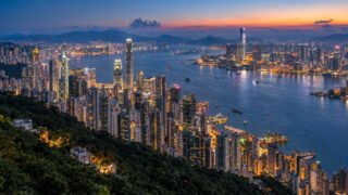 Hong Kong Island and Kowloon skylines seen across Victoria Harbour from Victoria Peak at blue hour