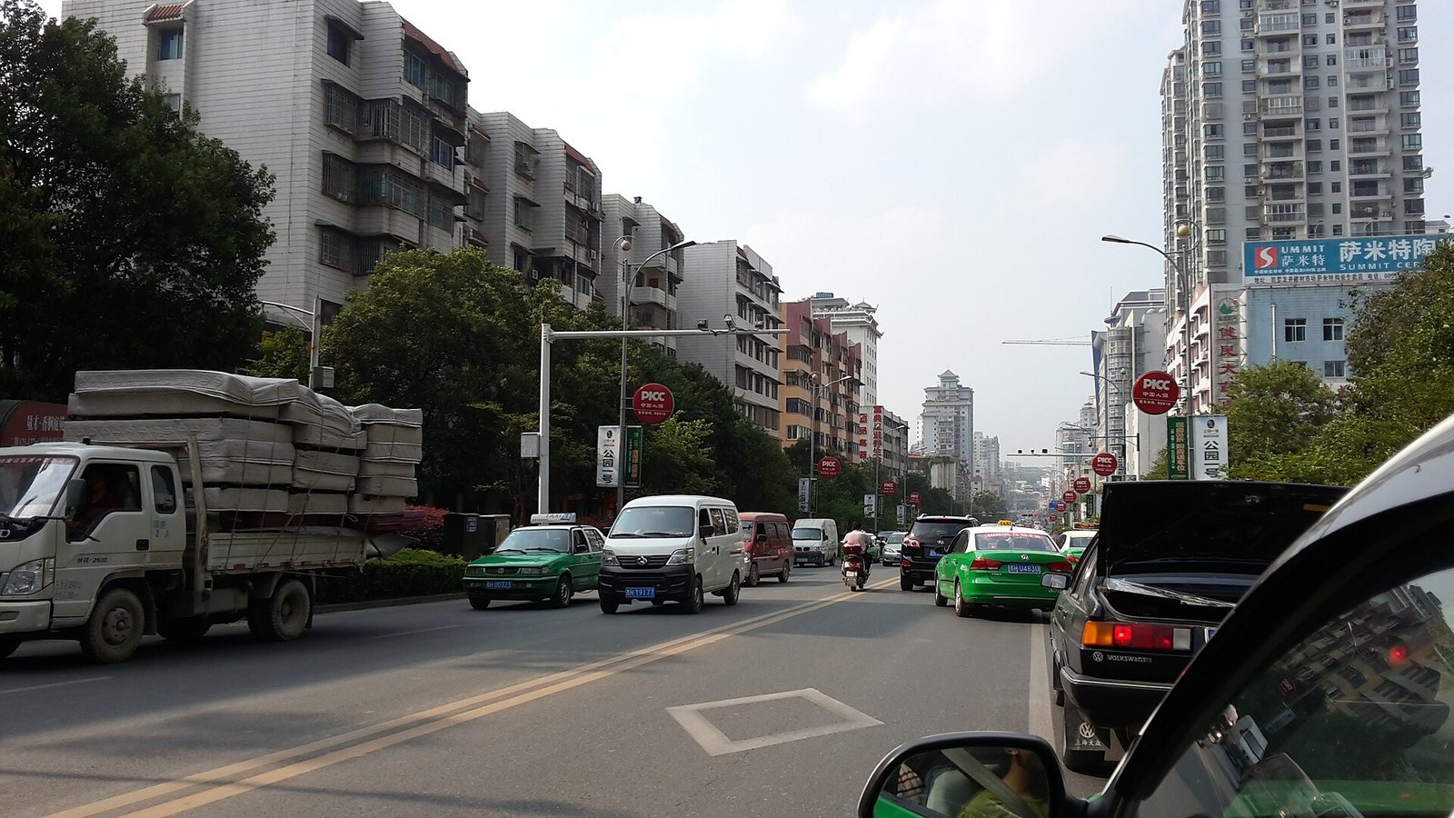 A main street in Kaili, Qiandongnan, with shops and traffic on an autumn afternoon