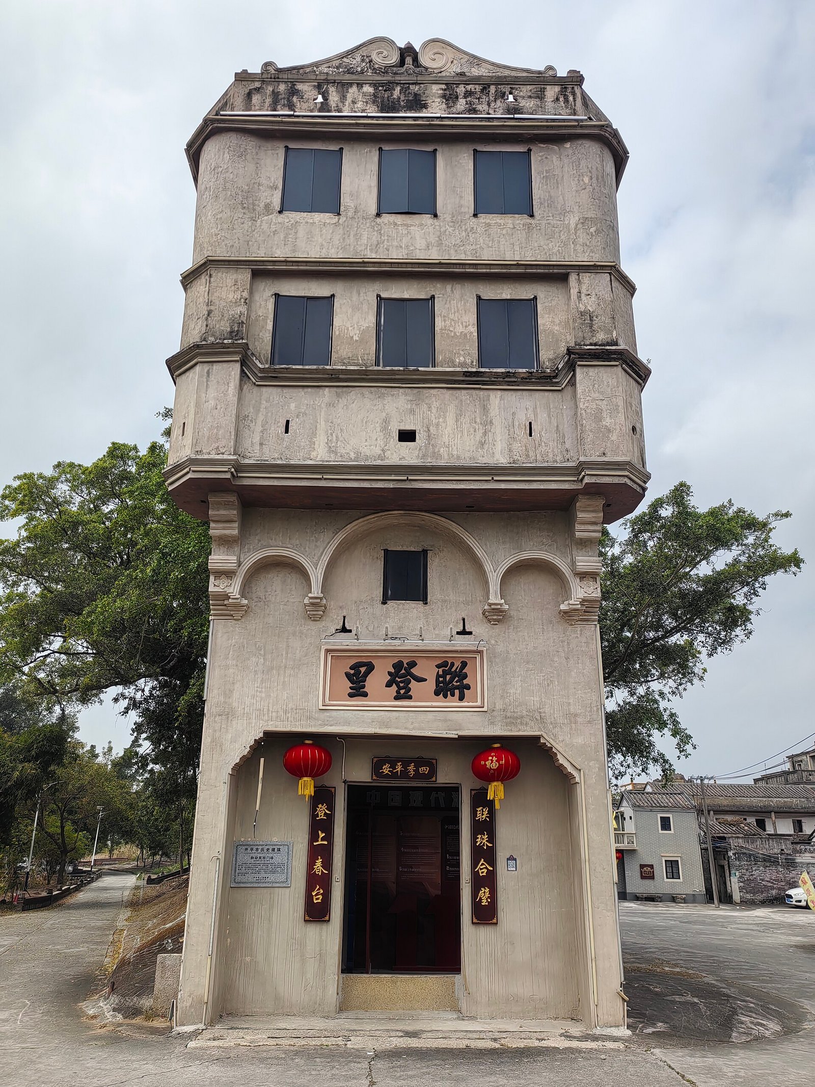 A five-storey concrete diaolou with arched doorway and Chinese name plaque, Kaiping