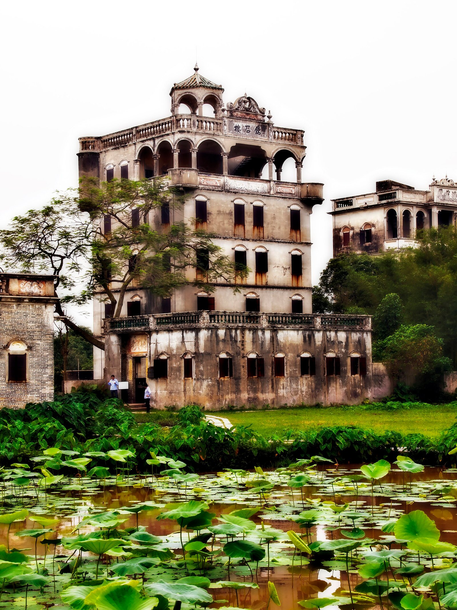 Mingshi Lou, a six-storey diaolou with colonnaded top floor, above a lotus pond
