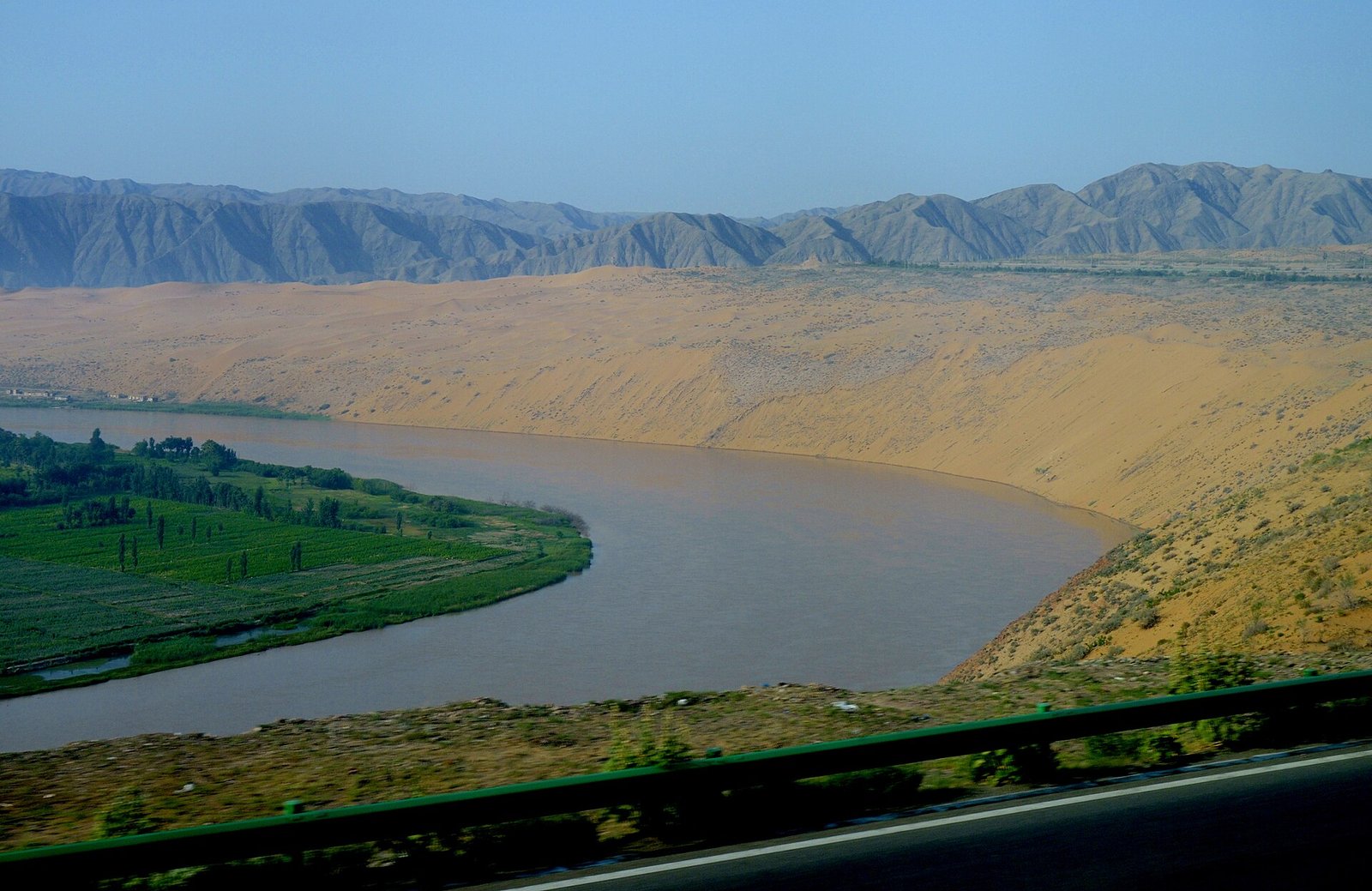 Yellow River bending around desert dunes seen from the top of the Shapotou sand slope