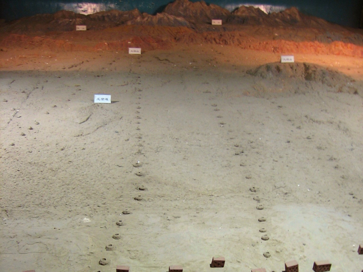 Turpan karez model showing a line of vertical shaft openings running down the desert slope toward the oasis