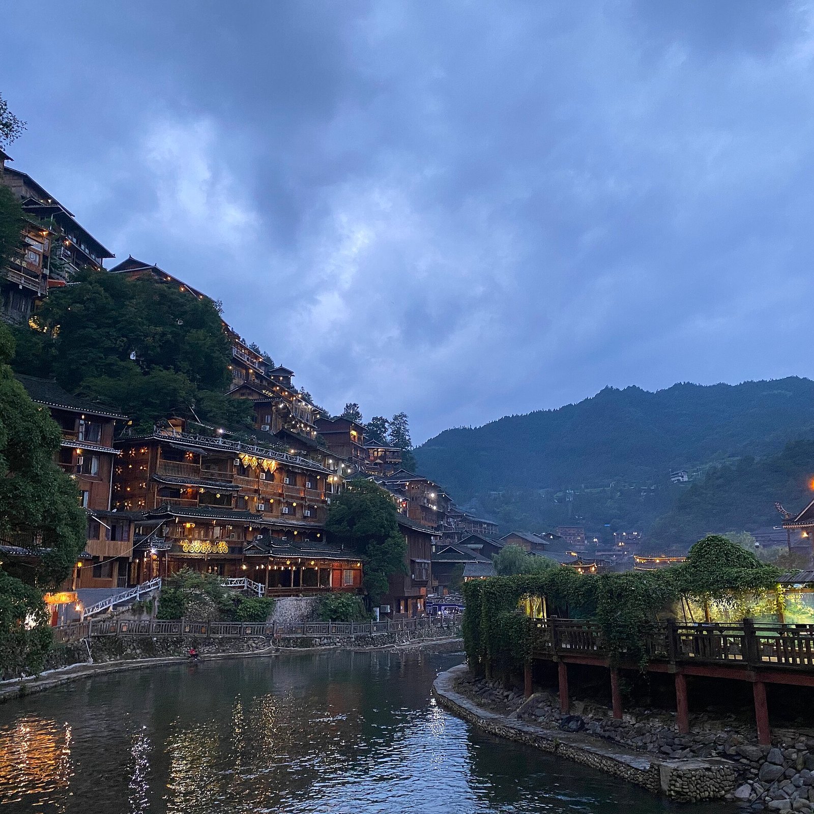 Xijiang: A Thousand Miao Households Lit Up at Dusk 2 Xijiang Miao Village at dusk with warm window lights covering both slopes above the river